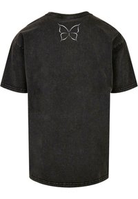 T-shirt noir à manches courtes en coton, présentant un graphisme de papillon blanc dans le haut du dos. Encolure ronde simple et ourlet droit.