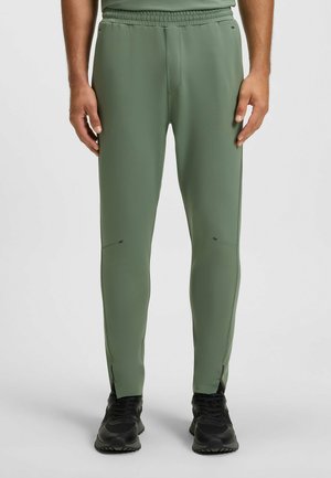 Green, fitted athletic pants with an elastic waistband, zippered accents at the ankles, and a smooth, sleek surface. Suitable for sports.