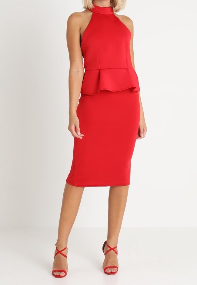Femme portant un haut rouge sans manches avec col halter et basque, associé à une jupe crayon assortie longueur genou et des talons rouges à brides.
