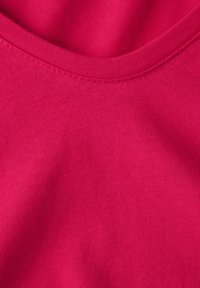 Fuksjowy materiał o gładkiej, elastycznej teksturze. Posiada okrągły dekolt i prążkowany wzór. Zbliżenie podkreśla szczegóły tkaniny.