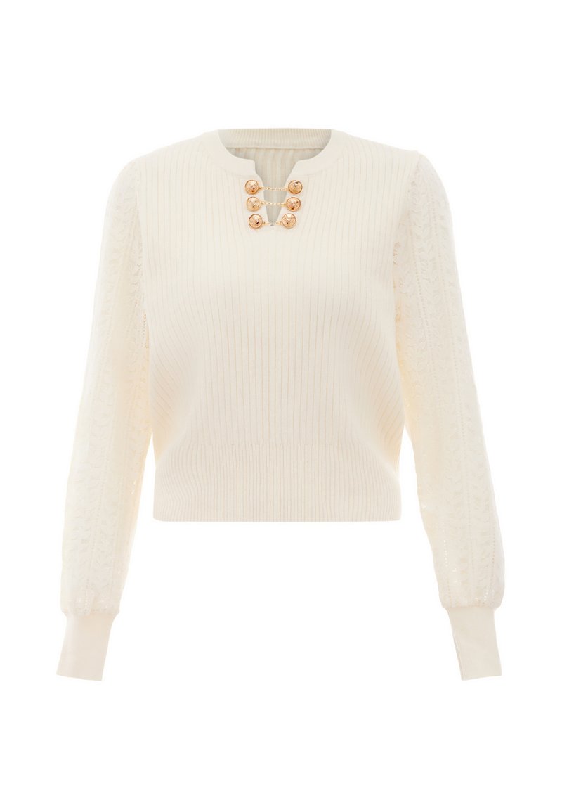 Kötött krémszínű pulóver bordás textúrával, puffadt csipkés ujjal és arany színű gombokkal a nyakán, rövid fazonú.