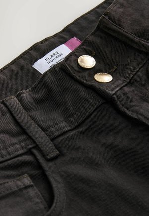 Svarta högmidjade flare jeans i ett texturerat tyg, med två metallknappar och en etikett som står "FLARE HIGH RISE."