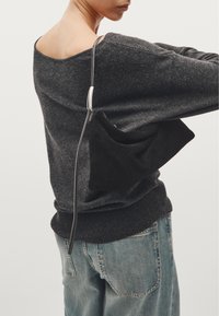 Black suede shoulder bag with a soft texture and a curved shape, featuring a thin black strap and polished silver hardware detail.