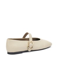 Zapato plano de cuero beige con punta afilada, correa en el tobillo y detalle de hebilla dorada. Textura suave y tacón bajo negro.