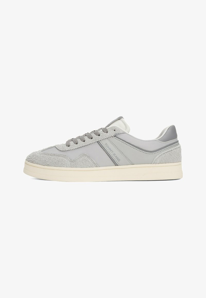 Baskets basses grises avec panneaux en daim texturé, lacets gris, semelle crème et logo "Tommy Jeans" sur le côté.
