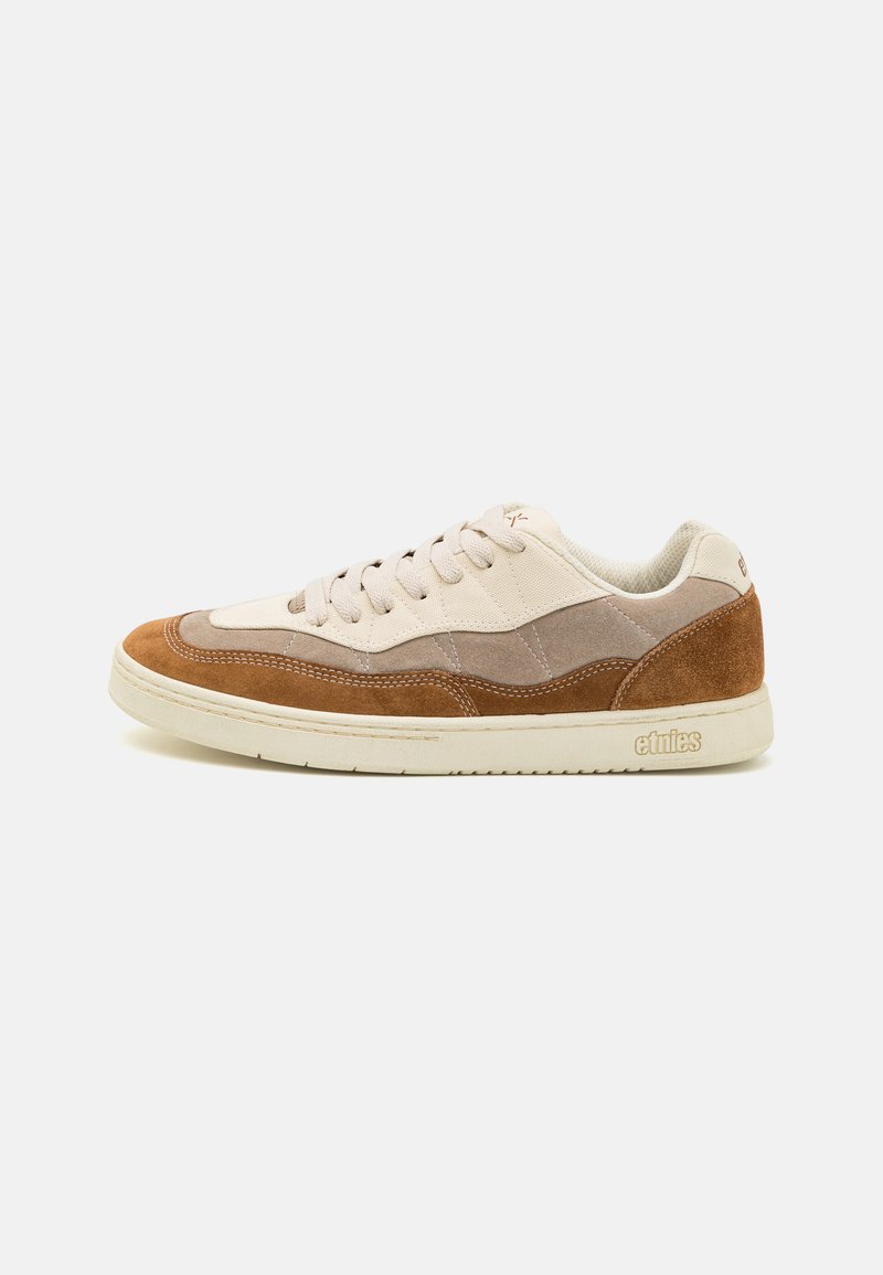 Beige ja pruun nubukist sneaker madala profiiliga, terava toe ja nööriga sulgemisega, kergete õmbluste ja logo detailiga kanna peal.