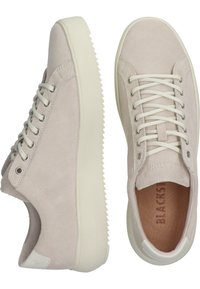 Light beige suede sneakers with a textured upper, white laces, and a thick white rubber sole featuring a zigzag pattern.