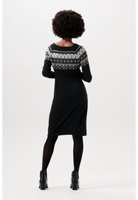 Svart långärmad klänning med en mönstrad yoke i vitt och grått. Tyget ser mjukt och stickat ut, med en figurnära silhuett och knälång fåll.