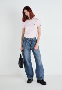 Rutet rosa t-skjorte med rund hals, sammen med løstsittende blå jeans og svarte platåsko. Svart skulderveske inkludert.
