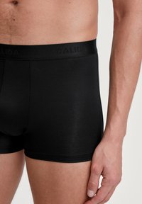 Zwarte boxershorts van gladde stof, met een brede, elastische tailleband met het "CALIDA"-logo en een smal ontwerp.