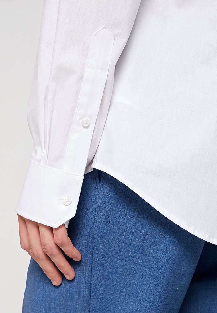 Weißes Langarmhemd mit geknöpften Manschetten, ausgestattet mit einer klaren Textur und einer taillierten Passform, sowie blauen strukturierten Hosen.