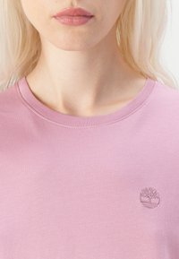 Lys rosa bomull t-skjorte med rund hals og subtilt trelogo i matchende broderi på venstre bryst. Glatt tekstur, uformell design.