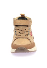 Zapatilla alta marrón que cuenta con una parte superior de tela y ante, cierre de cordones, correa de velcro y suela de goma con poco relieve.