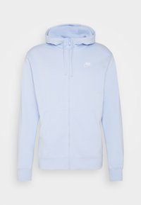 Ljusblå zip-up hoodie gjord av mjukt material, med en framficka, dragsko på huvan och vit Nike-logotyp på vänster bröst.