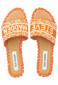 Sandali arancioni con suola piatta e cinturino intrecciato che presenta la scritta "STEVE MADDEN" in bianco, forma arrotondata e bordi decorativi a scallop.