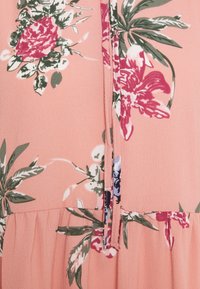 Kukallavärinen mekko kevyestä, teksturoidusta kankaasta; siinä on vaaleanpunainen tausta vihreillä lehdillä ja punaisilla kukilla; keskellä vetoketjusulku.