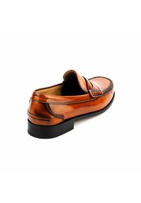 Mocasines de cuero marrón con un diseño elegante, punta redondeada, costuras intrincadas y un bajo tacón de goma negra. Textura suave con un acabado pulido.