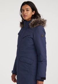 Marine parka jas met een bontachtige capuchon, ritsluiting, twee voorzakken en klittenbandsluitingen. Gemaakt van een duurzame stof met een soepele textuur.