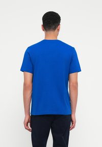 Zils īsām piedurknēm T-krekls ar apaļu kaklu, izgatavots no kokvilnas, ar vienota krāsa un vienkāršu dizainu, bez redzamām rakstām vai akcentiem.