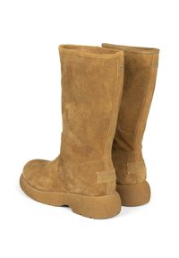 Botas altas de ante marrón con punta redondeada y superficie texturizada. Presentan una suela plana y acentos cosidos en el eje y el tacón.