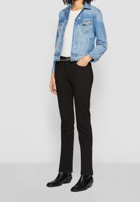 Ljusblå denimjacka, vit tajt skjorta, svarta slim-fit byxor och svarta ankelstövlar med en liten klack. Har ett silverkedjebelte.