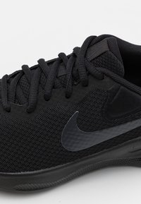 Crne sportske tenisice s mrežastim gornjim dijelom, ravnim vezicama i suptilnim Nike swoosh logotipom. Teksturirana potplat i glatki detalji upotpunjuju dizajn.