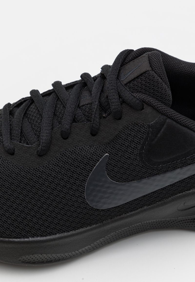 Schwarzer Sportschuh mit Netzobermaterial, flachen Schnürsenkeln und dezentem Nike-Swoosh-Logo. Strukturiertes Profil und glatte Akzente runden das Design ab.