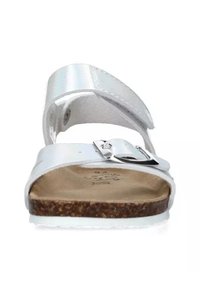 Sandal bianco con una fascia superiore lucida, fibbia argentata regolabile, piattaforma in sughero e suola testurizzata. Design semplice, accenti minimi.