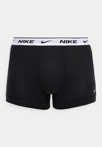 Μαύρα αντρικά εσώρουχα boxer με λευκό ελαστικό ζωνάρι μέσης που φέρει μαύρα λογότυπα Nike και μικρό λευκό λογότυπο Nike στο αριστερό πόδι.