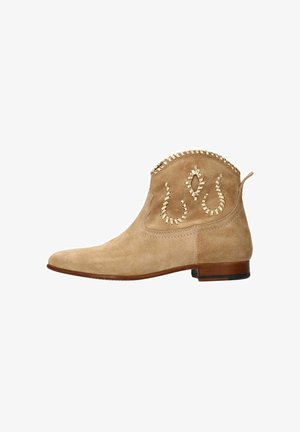 Beige suède enkelboot met een pointed toe, versierde stiksels en een decoratieve rand. Platte hak en een gedetailleerd patroon aan de zijkant.