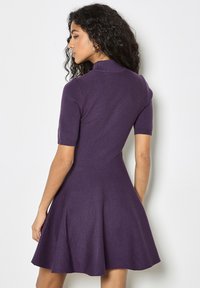 Vestido de punto de manga corta en púrpura profundo, con un corsé ajustado y falda acampanada, con una textura sutil y cuello acanalado.