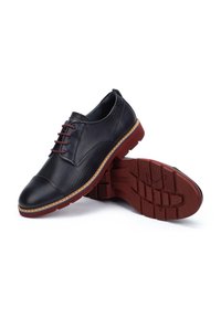Chaussures noires en cuir avec un design perforé, bout rond, lacets rouges et semelle en caoutchouc. Présente des accents de couture et une couleur de semelle contrastante.
