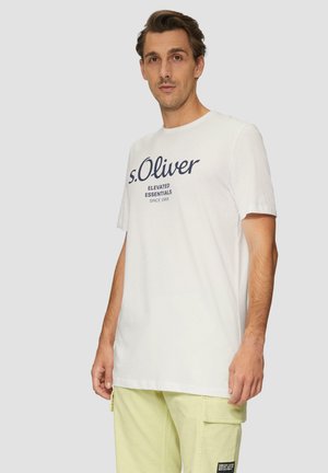 Biała koszulka z krótkim rękawem z granatowym napisem "s.Oliver Elevated Essentials" i luźnym krojem, stylizowana z jasnoszarymi spodniami.
