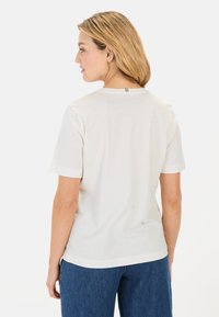 Kortærmet hvid t-shirt med rund hals, blødt stof og kontrastfarvede ribbede detaljer på ærmerne og ryggen.