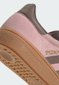 Sapatilhas de camurça rosa com detalhes em couro castanho, apresentando uma sola de borracha texturizada e letras em dourado "SPEZIAL". Logotipo visível no calcanhar.