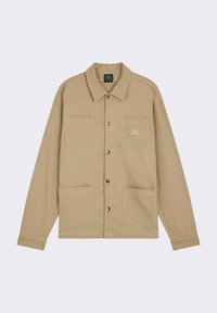 Veste en toile beige avec un col pointu, deux poches poitrine et deux poches inférieures. Présente des coutures visibles et des boutons-pression argentés.