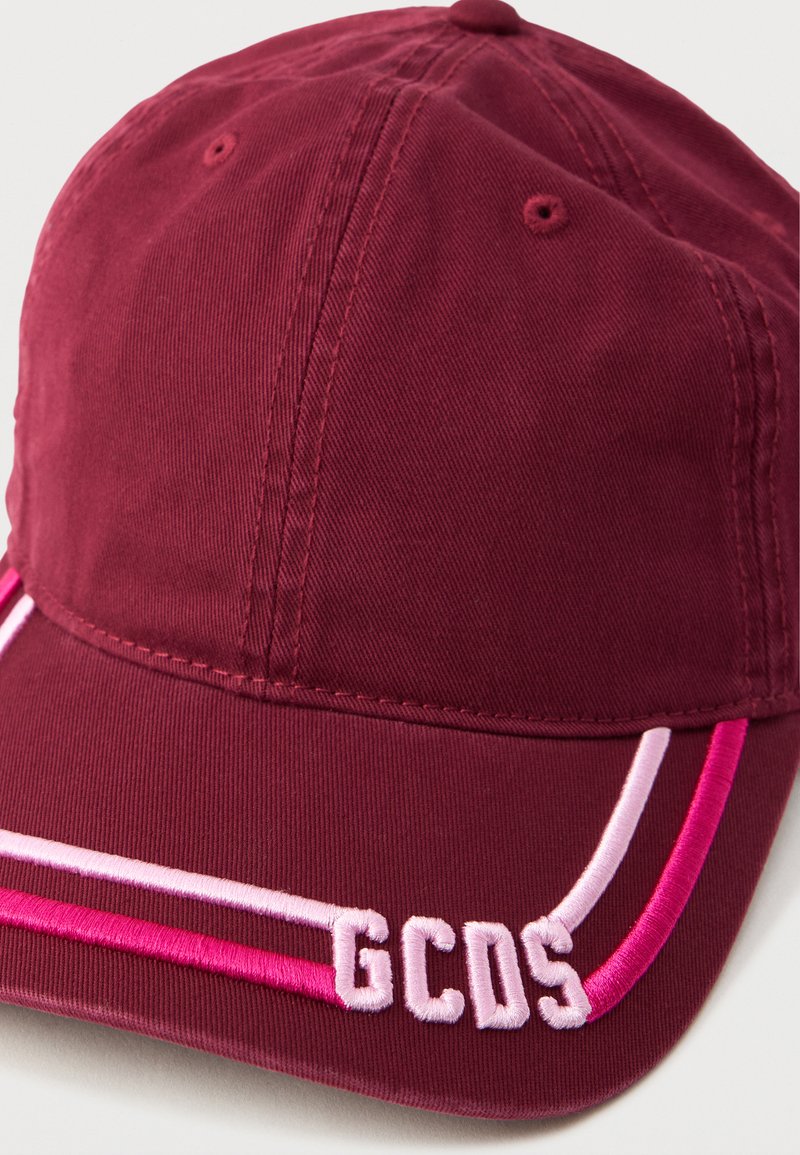 Casquette bordeaux avec des rayures contrastantes rose et blanche. Présente le logo brodé "GCOS" et un tissu texturé. Sangle ajustable à l'arrière.