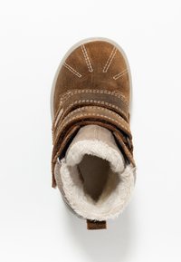 Bota de tobillo de ante marrón con dos correas, forro de piel sintética y punta redondeada. Presenta costuras decorativas y una suela de goma.
