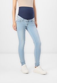 Trudna skinny traperice u svijetloplavoj denimu s mornarskom elastičnom trakicom u struku, s uskim krojem i klasičnim dizajnom s pet džepova.
