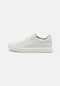 White leather sneakers with a textured finish, flat laces, and a rubber outsole. Soft brown interior lining and simple stitching details.
