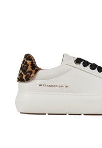 Hvide lædersneakers med sorte snørebånd, leopardmønster på hælen og gul tekst "ALEXANDER SMITH" på siden. Kraftigt såledesign.