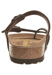 Brune kork såle sandal med flere tynne stropper, teksturert yttersåle og lav kilehæl. Innvendig har den et gult logo trykk.