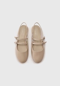 Chaussures Mary Jane en cuir vegan beige avec deux straps ajustables. Bout arrondi et texture lisse. Semelles plates avec un minimum de détails.