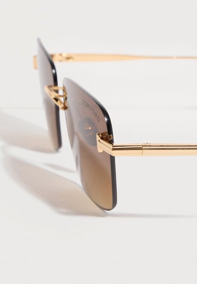 Square brown gradient lenses sunglasses with thin gold metal frame and arms, featuring brand name etched on the lens corner.