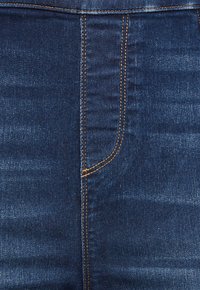 Mörkblå denimjeans med en jämn textur, med kontrasterande sömmar, en framficka på vänster sida och en hög midja.