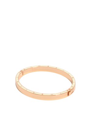 Brazalete circular de oro rosa con el nombre de la marca grabado alrededor del borde exterior y un pequeño cierre rectangular.