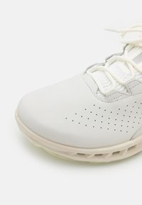 Hvit joggesko med en glatt læroverdel, perforerte detaljer, hvite snøringer og en lys, polstret såle.
