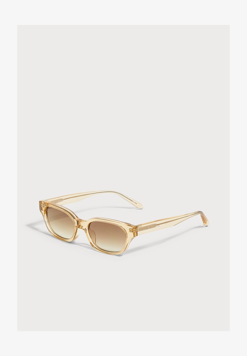 Lunettes de soleil rectangulaires translucides marron clair avec des verres marron dégradés reposant sur une surface blanche.
