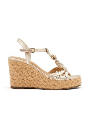 Sandal med kilehæl og vævet jute-platform, metallisk gyldne fletede stropper, ankelspænde og knyttet T-stropdesign.