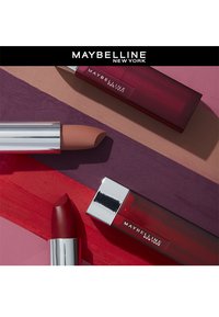 Maybelline läppstift i olika nyanser: en ljus nude-kapsel med ett metalliskt lock, en djup röd kapsel och en stav i ett klart hölje med en röd bas.